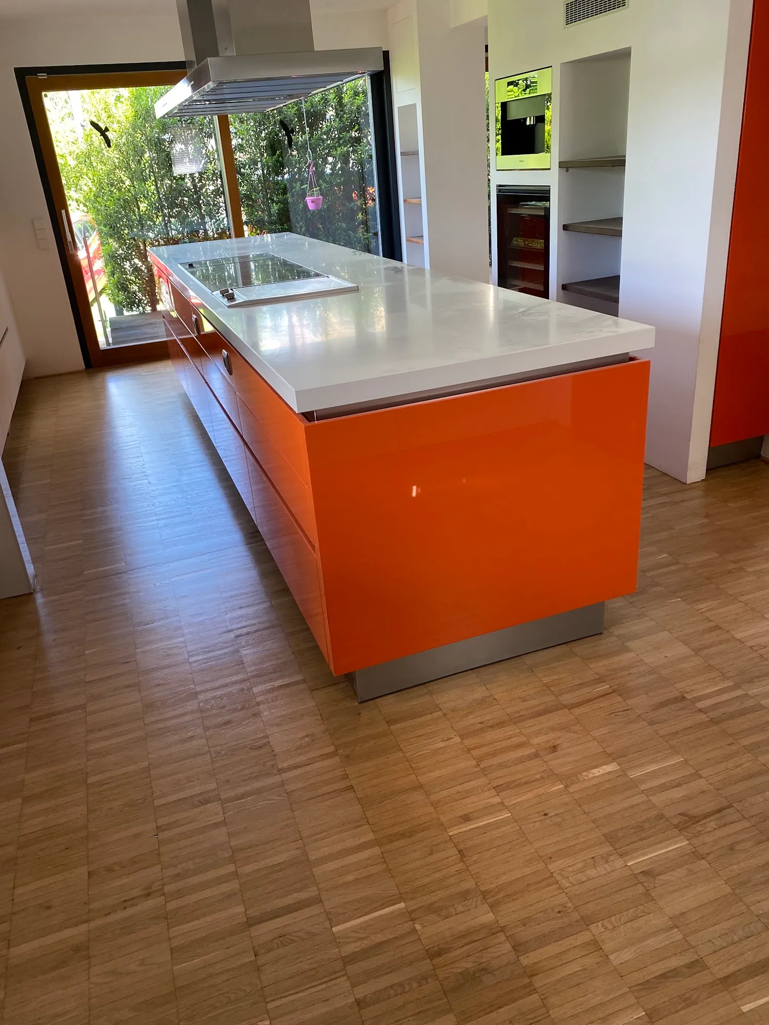 Moderne Küche mit oranger Kochinsel und Würfelparkett